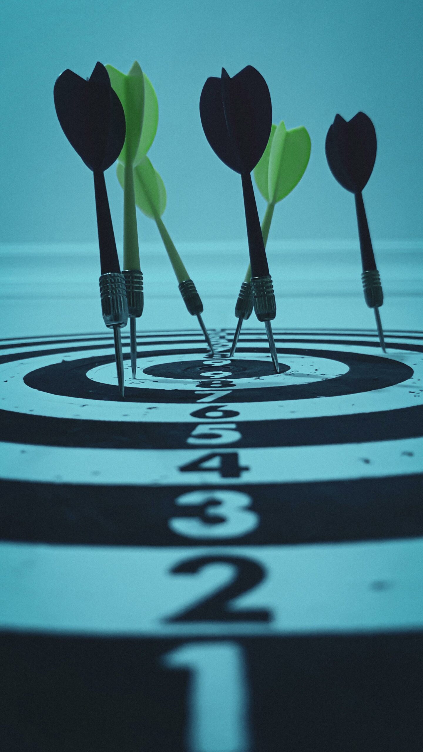 Close-up view of darts hitting a bullseye on a target board, symbolizing precision and focus.