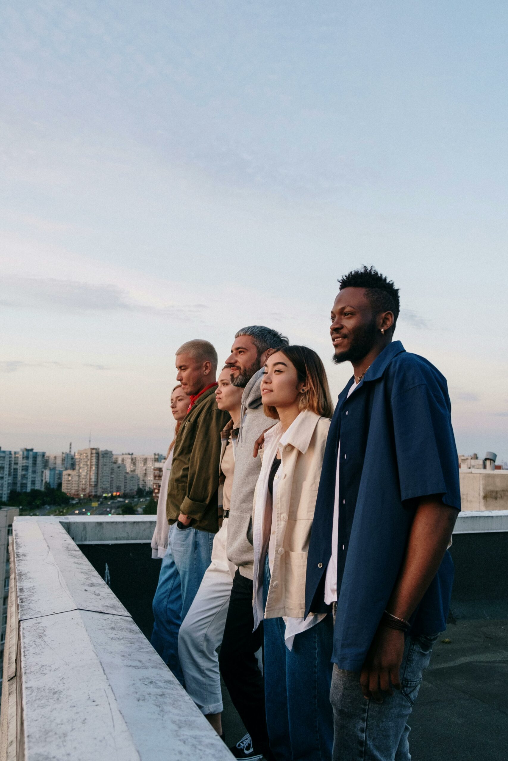 A diverse group of friends relaxing together on a rooftop at sunset, enjoying the cityscape view.
